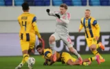 Raz Shlomo, du Maccabi Tel Aviv, au centre, lutte pour le ballon avec Pavel Sulc de Lyon, au sol, lors du match de football de la phase de ligue de l'Europa League entre le Maccabi Tel Aviv et Lyon, à Backa Topola, en Serbie, le 27 novembre 2025. (AP Photo/Darko Vojinovic)
