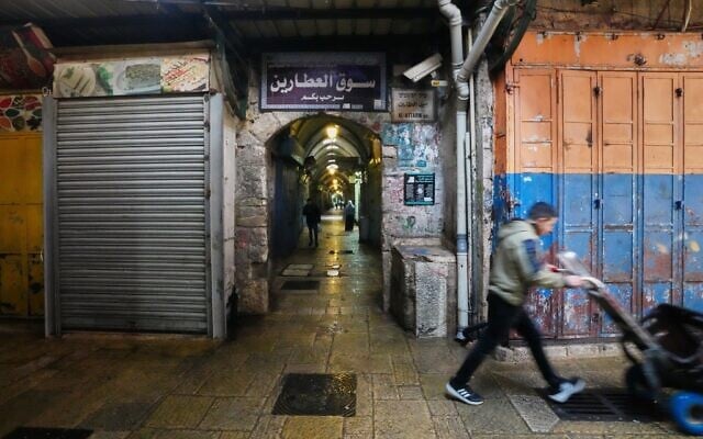 Un homme pousse une charrette à bras devant des boutiques fermées dans la vieille ville de Jérusalem, le 27 mars 2026, alors que le quartier reste interdit aux visiteurs en raison de la guerre avec l'Iran. (Crédit : AP Photo/Mahmoud Illean) Un homme pousse une charrette à bras devant des boutiques fermées dans la vieille ville de Jérusalem, le 27 mars 2026, alors que le quartier reste interdit aux visiteurs en raison de la guerre avec l'Iran. (Crédit : AP Photo/Mahmoud Illean)