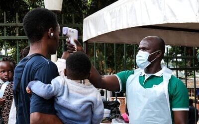 Un agent de santé muni d'un thermomètre contrôle la température des patients devant l'hôpital musulman de Kibuli, à Kampala, en Ouganda, le 16 mai 2026. (Crédit : Hajarah Nalwadda/AP) Un agent de santé muni d'un thermomètre contrôle la température des patients devant l'hôpital musulman de Kibuli, à Kampala, en Ouganda, le 16 mai 2026. (Crédit : Hajarah Nalwadda/AP)