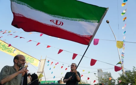 Un homme brandit un drapeau iranien lors d'une fête de rue célébrant l'Aïd al-Ghadir, fête chiite commémorant le jour où le prophète Mahomet a désigné son successeur, Ali, vénéré comme le premier imam chiite, à Téhéran, en Iran, le 4 juin 2026. (Crédit: AP/Vahid Salemi)