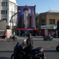 Des motos circulent près de la résidence où le défunt guide suprême iranien, l'ayatollah Ali Khamenei (représenté sur une banderole), a été tué lors de frappes américaines et israéliennes le 28 février, à Téhéran, en Iran, le samedi 6 juin 2026. (AP Photo/Vahid Salemi)