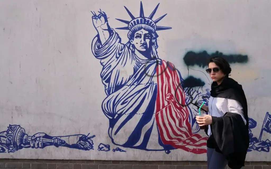 Une femme passant devant une fresque anti-américaine sur le mur de l'ancienne ambassade des États-Unis, aujourd'hui transformée en musée, à Téhéran, en Iran, le 12 juin 2026. (Crédit : Vahid Salemi/AP)