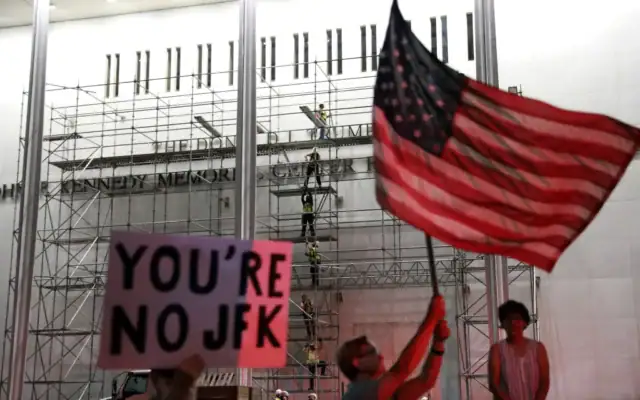 Des personnes attendent que le nom du président américain Donald Trump soit retiré du John F. Kennedy Center for the Performing Arts à Washington, vendredi 12 juin 2026. (Crédit: AP Photo/Rahmat Gul)
