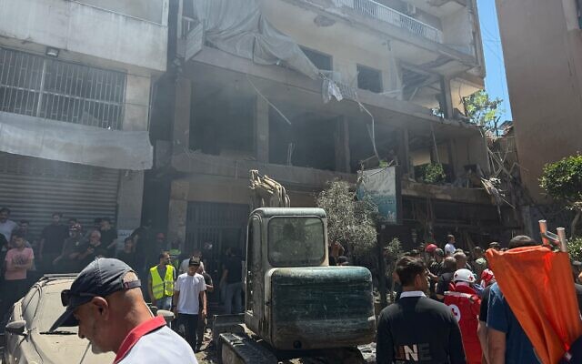 Des personnes réunies sur le site d’une frappe aérienne qui a frappé ce que l’armée israélienne a qualifié de centre de commandement du Hezbollah - bastion historique du groupe terroriste chiite libanais connu sous le nom de la Dahiyeh -, dans la banlieue sud de Beyrouth, au Liban, le 14 juin 2026. (Crédit : Bilal Hussein/AP)
