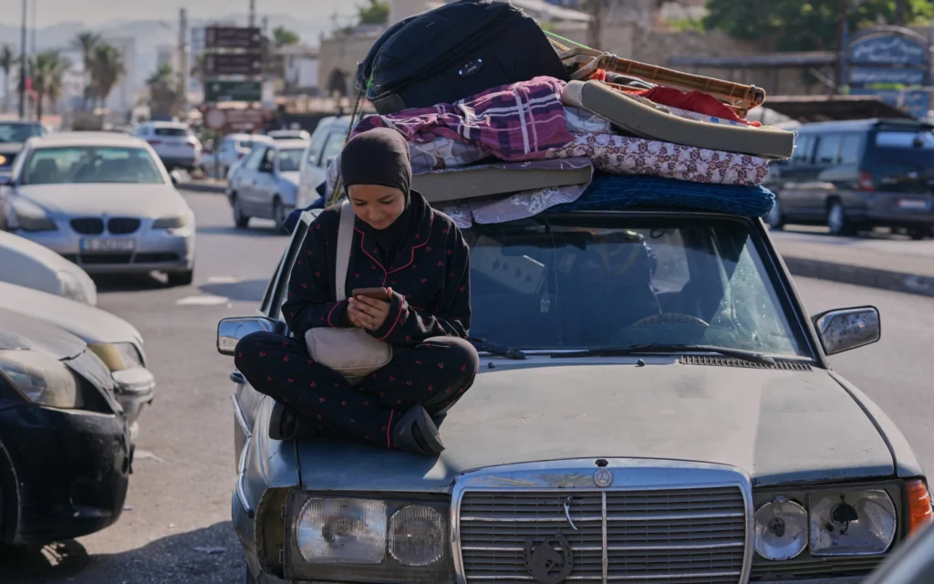 Une femme déplacée consulte son téléphone portable alors qu'elle attend de pouvoir retourner dans son village, après l'annonce d'un premier accord de cessez-le-feu entre les États-Unis et l'Iran, dans la ville portuaire de Sidon, au sud du Liban, le 15 juin 2026. (Crédit : AP/Mohammed Zaatari)