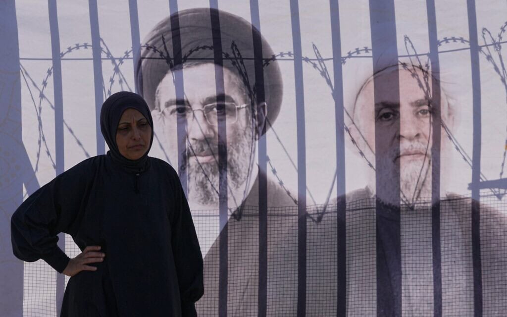 Une sympathisante du groupe terroriste chiite libanais du Hezbollah se tenant près d’une banderole sur laquelle figurent les portraits du guide suprême iranien Mojtaba Khamenei (à gauche) et du chef du Hezbollah, le cheikh Naïm Qassem, alors qu’elle commémore l’Achoura,à la Dahiyeh, bastion historique du Hezbollah, dans la banlieue sud de Beyrouth, au Liban, le 26 juin 2026. (Crédit : Hussein Malla/AP Photo)