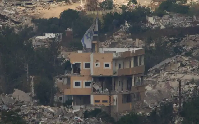 Un drapeau israélien sur un bâtiment détruit dans le sud du Liban, vu depuis le nord d’Israël, le 27 juin 2026. (Crédit: AP Photo/Ariel Schalit)