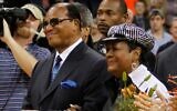 Louis Farrakhan, ministre de la Nation de l'Islam, et son épouse, Khadijah, regardant leur petit-fils, Mustapha Farrakhan, étudiant en dernière année à l'université de Virginie, être mis à l'honneur aux côtés d'autres étudiants de dernière année avant le match de basket-ball universitaire de la NCAA opposant l'université de Virginie à celle de Caroline du Nord à Charlottesville, le 1ᵉʳ mars 2011. (Crédit : Steve Helber/AP)