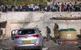 Des civils et des forces de sécurité sur les lieux où un missile tiré par le Hezbollah depuis le Liban a frappé un parking à Safed, causant d’importants dégâts, le 10 avril 2026. (David Cohen/Flash90)