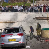Des civils et des forces de sécurité sur les lieux où un missile tiré par le Hezbollah depuis le Liban a frappé un parking à Safed, causant d’importants dégâts, le 10 avril 2026. (David Cohen/Flash90)