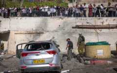Des civils et des forces de sécurité sur les lieux où un missile tiré par le Hezbollah depuis le Liban a frappé un parking à Safed, causant d’importants dégâts, le 10 avril 2026. (David Cohen/Flash90)