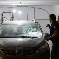 La police inspectant une voiture endommagée devant le domicile du vice-président de la Cour suprême, Noam Sohlberg, dans l'implantation d'Alon Shvut en Cisjordanie, après que des Haredim ont attaqué la maison pour protester contre l'incarcération de ceux qui n'ont pas respecté les ordres de conscription de l'armée israélienne, le 3 juin 2026. (Crédit : Chaïm Goldberg/Flash90)