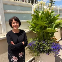 L’artiste Farideh Golbahar avec les fleurs qu’elle cultive chez elle, à Jérusalem, en mai 2026 (Jessica Steinberg/Times of Israel)