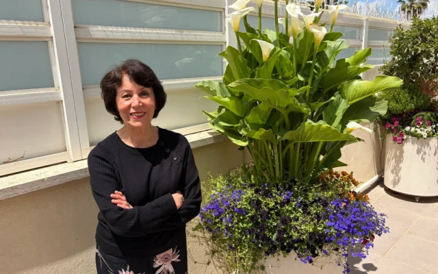 L’artiste Farideh Golbahar avec les fleurs qu’elle cultive chez elle, à Jérusalem, en mai 2026 (Jessica Steinberg/Times of Israel)