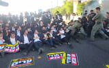 La police affronte des manifestants ultra-orthodoxes, dont certains portent des étoiles jaunes rappelant celles imposées aux Juifs pendant la Shoah, lors d’une manifestation haredi contre le service militaire à l’échangeur de Ben Shemen, dans le centre d’Israël, le 11 juin 2026. (Crédit : Police israélienne)