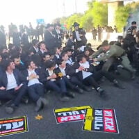 La police affronte des manifestants ultra-orthodoxes, dont certains portent des étoiles jaunes rappelant celles imposées aux Juifs pendant la Shoah, lors d’une manifestation haredi contre le service militaire à l’échangeur de Ben Shemen, dans le centre d’Israël, le 11 juin 2026. (Crédit : Police israélienne)