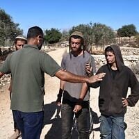 Un agriculteur palestinien (à gauche) tente d'empêcher des résidents d'implantations israéliens de s'approcher d'une oliveraie alors que la récolte est en cours, près du village palestinien de Silwad, au nord-est de Ramallah en Cisjordanie, le 29 octobre 2025. (Crédit : Zain JAAFAR/AFP)