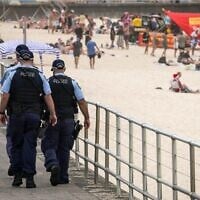 Des policiers patrouillent près des baigneurs le jour de Noël à Bondi Beach, à Sydney, le 25 décembre 2025. (Crédit : David Gray/AFP)