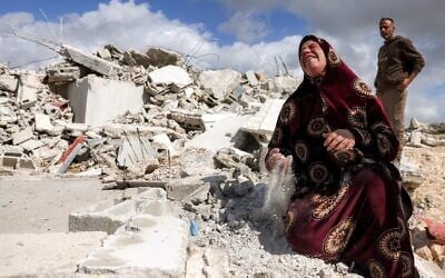 Une Palestinienne tient dans ses mains la poussière des décombres de sa maison, démolie par les forces de sécurité israéliennes, dans le village palestinien de Beit Awwa, au sud-ouest de la Cisjordanie, le 11 février 2026. (Crédit : Hazem Bader/AFP)