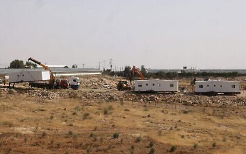 De nouveaux logements préfabriqués destinés à un avant-poste sont installés le long d'une route menant au village palestinien d'Umm al-Khair, entre le nouvel avant-poste de Karmel et l'implantation israélienne de Karmel, au sud de la ville de Yatta, dans le sud de la Cisjordanie palestinienne, le 20 mai 2026. (Crédit : Hazem Bader/AFP)