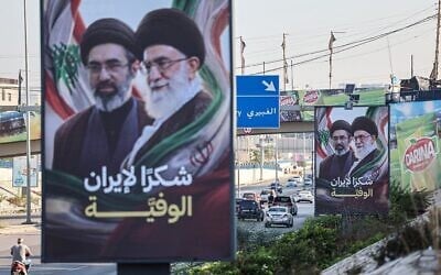 Des voitures et des motos passent devant des panneaux publicitaires représentant le guide suprême iranien, l'ayatollah Mojtaba Khamenei (à gauche), et son défunt père, Ali Khamenei (à droite), accompagnés du slogan « Merci, Iran fidèle », à Beyrouth, le 22 juin 2026. (Crédit : Anwar AMRO / AFP)