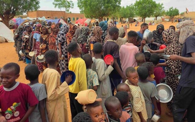 Des femmes et des enfants attendent leur tour pour recevoir de la nourriture distribuée gratuitement dans le camp de déplacés d'al-Mohayra, près de la ville d'El-Obeid, dans la région du Kordofan du Sud, le 29 juin 2026. (Crédit : AFP)