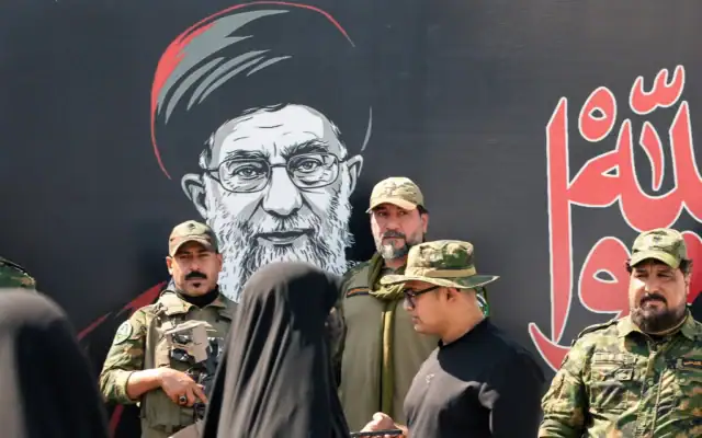 Les forces de sécurité devant une banderole représentant le guide suprême iranien assassiné, Ali Khamenei, à Najaf, à la veille de son cortège funèbre dans cette ville irakienne, le 7 juillet 2026. (Crédit: Qassem al-KAABI / AFP)