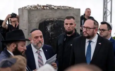 Le grand rabbin de Pologne, Michael Schudrich (2e à partir de la gauche), récite le Kaddish devant le monument commémorant le massacre de Jedwabne pendant la guerre, lors des cérémonies rendant hommage à la mémoire des habitants juifs de la ville assassinés le 10 juillet 1941 par leurs voisins polonais, à Jedwabne, dans le nord-est de la Pologne, le 10 juillet 2026. (Crédit: Wojtek RADWANSKI / AFP)