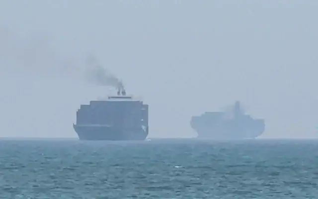 Cette image extraite d’une vidéo de l’AFPTV datée du 12 juillet 2026 montre des cargos jetant l’ancre près du détroit d’Ormuz, au large de la côte orientale des Émirats arabes unis, à Khor Fakkan (Crédit: AFPTV/AFP)