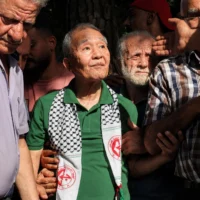 Kozo Okamoto (au centre) — seul survivant de l’unité commando de trois hommes de l’« Armée rouge japonaise » (JRA) qui a tué 26 personnes lors d’un attentat contre l’aéroport israélien de Lod le 30 mai 1972 — assiste à une cérémonie organisée par des militants palestiniens pour marquer le 50e anniversaire de l’attentat terroriste de Lod, à Beyrouth, la capitale du Liban, le 30 mai 2022. (Crédit: JOSEPH EID/AFP)