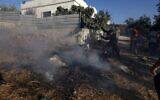 Des habitants palestiniens éteignent un incendie après que des véhicules et des habitations ont été incendiés lors d'une attaque qui aurait été perpétrée par des résidents d'implantations israéliens dans le village palestinien de Sarra, à l'ouest de la ville de Naplouse, en Cisjordanie, le 24 juillet 2026. (Crédit : Jaafar Ashtiyeh/AFP)