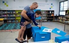 Un homme et son fils votant lors des élections législatives, à Tel Aviv, le 1ᵉʳ novembre 2022. (Crédit : Oded Balilty/AP)