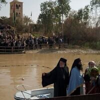 Le patriarche orthodoxe grec de Jérusalem, Théophile III (au centre), se tenant debout dans une barque lors d’une cérémonie sur les eaux du Jourdain, dans le cadre d’une cérémonie de baptême organisée à l’occasion de la fête orthodoxe de l’Épiphanie sur le site baptismal de Qasr al-Yahud, près de Jéricho, en Cisjordanie, en Israël, le 18 janvier 2024 (Crédit : Leo Correa/AP)