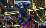L'Israélien Noam Bettan monte sur scène en brandissant le drapeau de son pays avant la grande finale du 70e Concours Eurovision de la chanson, à Vienne, en Autriche, le 16 mai 2026. (Crédit : AP/Martin Meissner)