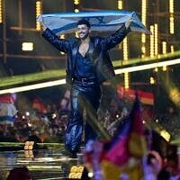 L'Israélien Noam Bettan monte sur scène en brandissant le drapeau de son pays avant la grande finale du 70e Concours Eurovision de la chanson, à Vienne, en Autriche, le 16 mai 2026. (Crédit : AP/Martin Meissner)