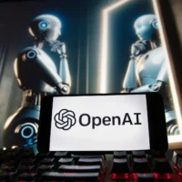 Le logo d’OpenAI apparaît sur un téléphone portable, à côté d’une image générée par DALL·E, le modèle de génération d’images à partir de texte d’OpenAI, le 8 décembre 2023, à Boston. (Crédit : Michael Dwyer/AP)