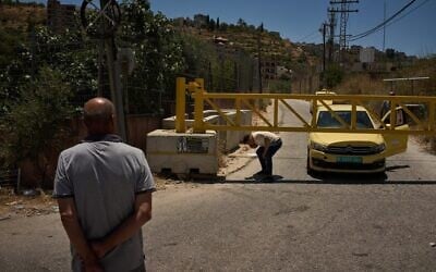 Un Palestinien franchissant un barrage routier érigé par l'armée israélienne aux entrées du village de Sinjil, en Cisjordanie, le 1ᵉʳ juillet 2026. (Crédit : Leo Correa/AP) Un Palestinien franchissant un barrage routier érigé par l'armée israélienne aux entrées du village de Sinjil, en Cisjordanie, le 1ᵉʳ juillet 2026. (Crédit : Leo Correa/AP)