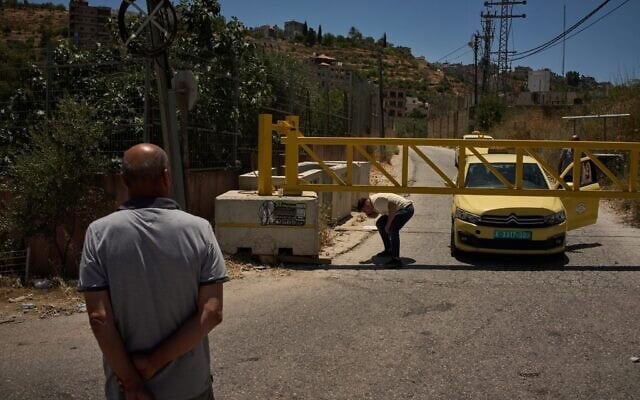 Un Palestinien franchissant un barrage routier érigé par l'armée israélienne aux entrées du village de Sinjil, en Cisjordanie, le 1ᵉʳ juillet 2026. (Crédit : Leo Correa/AP)