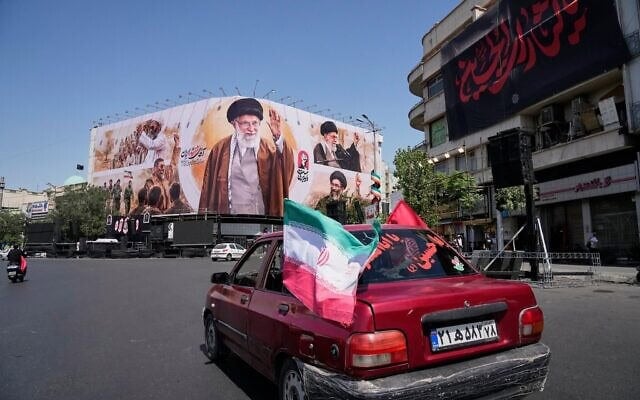 Des véhicules passant devant un panneau d’affichage représentant le défunt guide suprême iranien, l’ayatollah Ali Khamenei, sur la place de la Révolution islamique, à Téhéran, en Iran, le 5 juillet 2026. (Crédit : Vahid Salemi/AP)