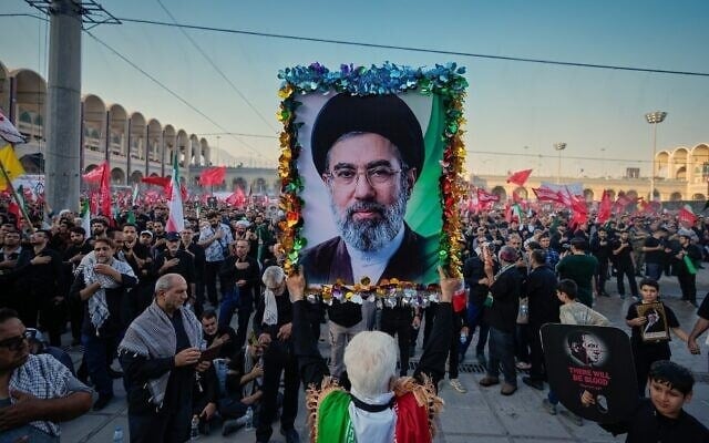 Un homme tient une photo du nouveau Guide suprême iranien, Mojtaba Khamenei lors des cérémonies funéraires organisées en l’honneur du Guide suprême assassiné, l’ayatollah Ali Khamenei, et des membres de sa famille, à la Grande Mosquée Imam Khomeini Mosalla, à Téhéran, en Iran, le 5 juillet 2026. (Crédit : Altaf Qadri/AP)