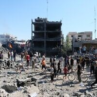 Des Palestiniens se rassemblent près du site d'une frappe de drone israélien dans le quartier de Sabra, à Gaza-City, le 12 juillet 2026. (Crédit : AP Photo/Jehad Alshrafi)