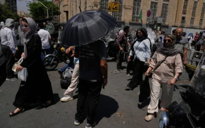 Un homme s’abrite du soleil sous un parapluie à un carrefour, près du Grand Bazar de Téhéran, en Iran, le 16 juillet 2026. (Crédit : Vahid Salemi/AP)