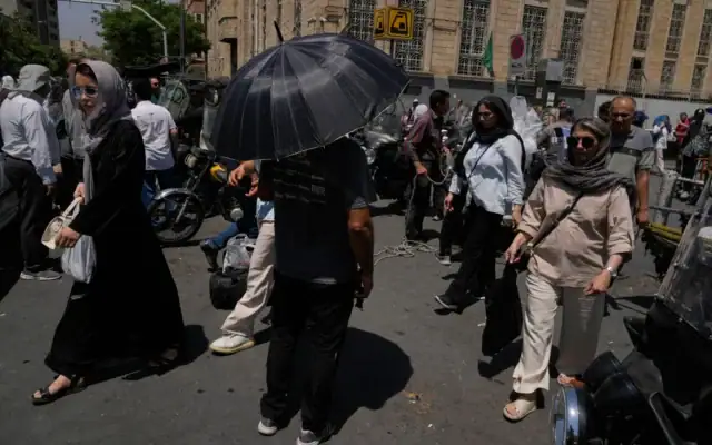 Un homme s’abrite du soleil sous un parapluie à un carrefour, près du Grand Bazar de Téhéran, en Iran, le 16 juillet 2026. (Crédit : Vahid Salemi/AP)