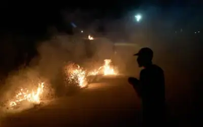 Un Palestinien se tient près d'un feu de broussailles allumé sur le bord de la route pour empêcher une attaque de résidents d'implantations israéliens dans le village de Sinjil, en Cisjordanie, le 17 juillet 2026. (AP/Leo Correa) Un Palestinien se tient près d'un feu de broussailles allumé sur le bord de la route pour empêcher une attaque de résidents d'implantations israéliens dans le village de Sinjil, en Cisjordanie, le 17 juillet 2026. (AP/Leo Correa)