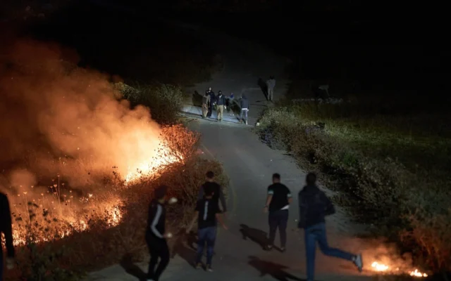 Des partisans dumouvement pro-implantations israéliens (en haut) et des Palestiniens s'affrontent alors qu'un feu fait rage au bord d'une route aux abords du village de Sinjil, en Cisjordanie, le 17 juillet 2026. (Crédit: AP/Leo Correa)