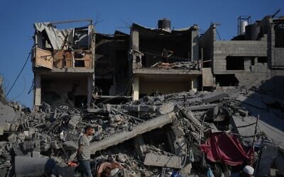 Des Palestiniens inspectent un bâtiment détruit après une frappe aérienne israélienne à Deir al-Balah, dans le centre de la bande de Gaza, le 19 juillet 2026. (Crédit : AP Photo/Abdel Kareem Hana)