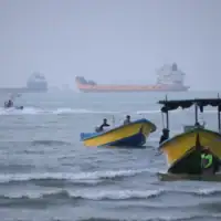 De petites embarcations longeant le rivage tandis que des cargos et d’autres navires marchands sont ancrés dans le détroit d’Ormuz, au large de Bandar Abbas, en Iran, le 27 juillet 2026. (Crédit : Razieh Poudat/ISNA via AP)