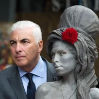 Mitch Winehouse pose pour une photo avec une statue de sa défunte fille, Amy Winehouse, après son inauguration au Stables Market de Camden, à Londres, le 14 septembre 2014. (Crédit : AP/Tim Ireland/Archives)
