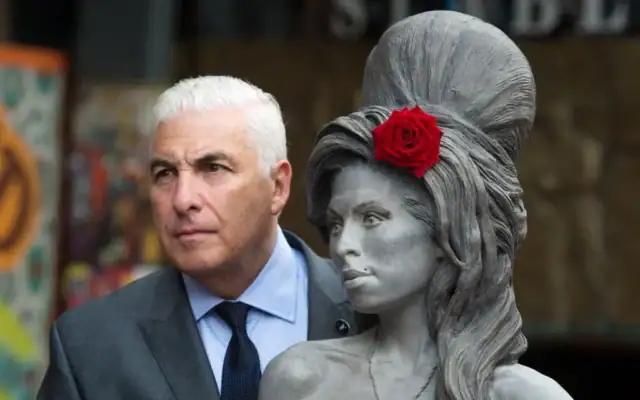 Mitch Winehouse pose pour une photo avec une statue de sa défunte fille, Amy Winehouse, après son inauguration au Stables Market de Camden, à Londres, le 14 septembre 2014. (Crédit : AP/Tim Ireland/Archives)