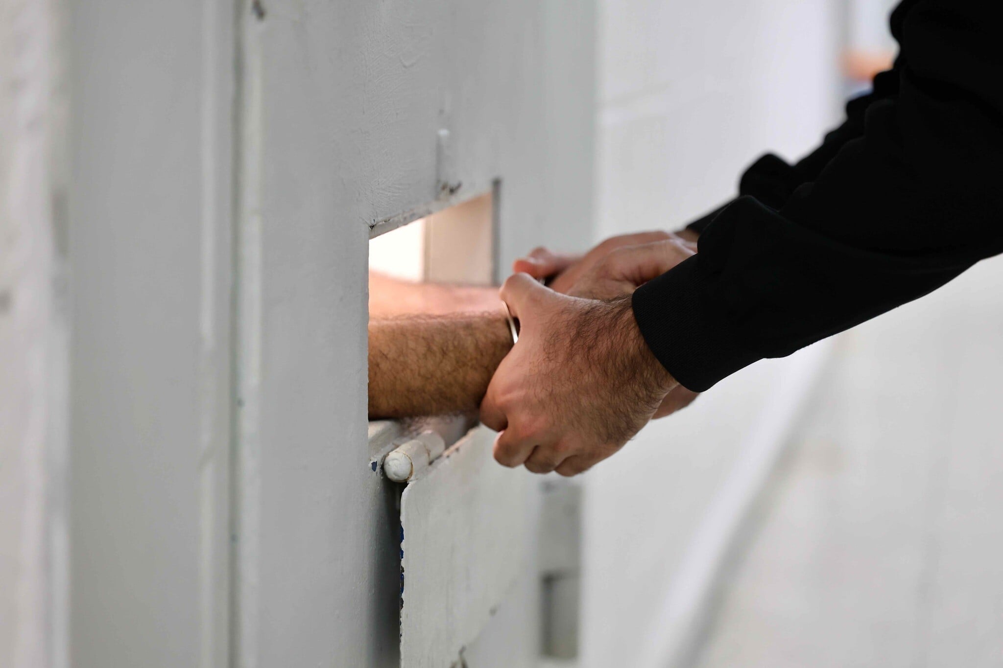 Un gardien menottant les mains d'un prisonnier, à la prison de Givon, à Ramle, le 11 janvier 2026. (Crédit : Oren Cohen/Flash90) Un gardien menottant les mains d'un prisonnier, à la prison de Givon, à Ramle, le 11 janvier 2026. (Crédit : Oren Cohen/Flash90)